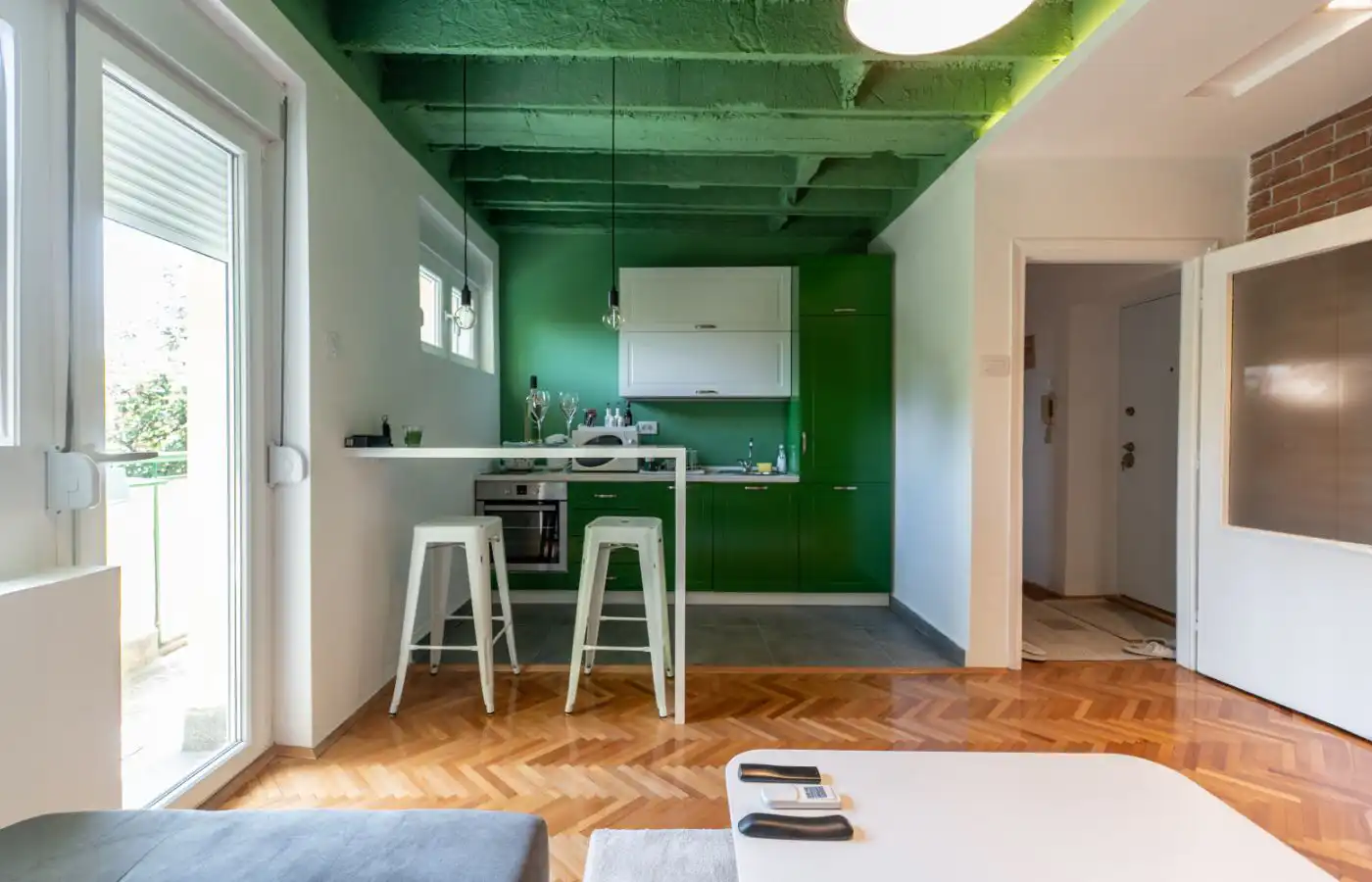 Petit salon avec un espace cuisine optimisé, des couleurs contrastées et un mobilier compact pour un aménagement fonctionnel et stylé.