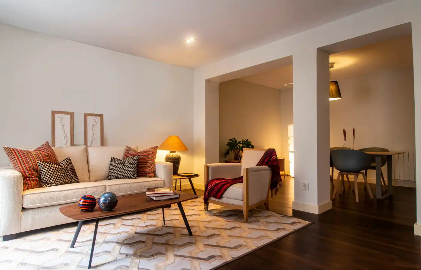 Salon moderne et lumineux avec décoration minimaliste, canapé beige, coussins colorés et table basse en bois, illustrant une transformation réussie d’espace de vie.